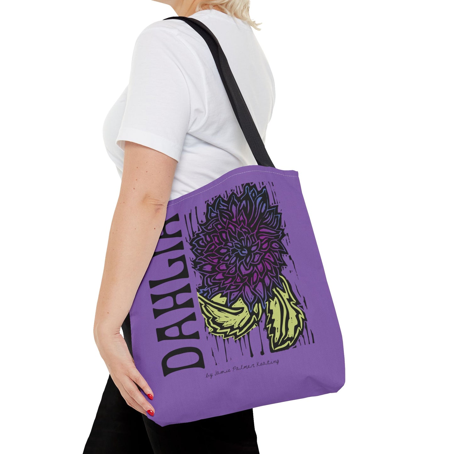 Person holding a purple tote bag with floral design and text