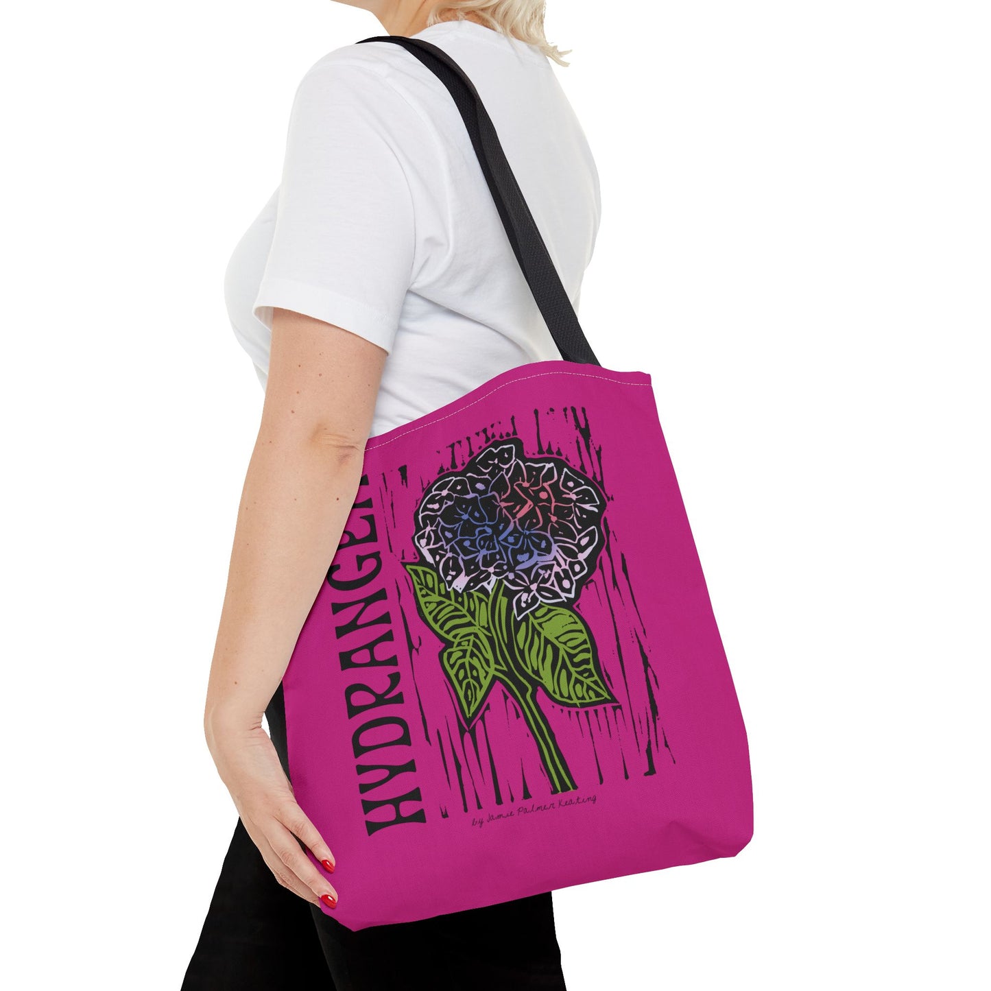 Person holding a pink tote bag with a floral design and text.