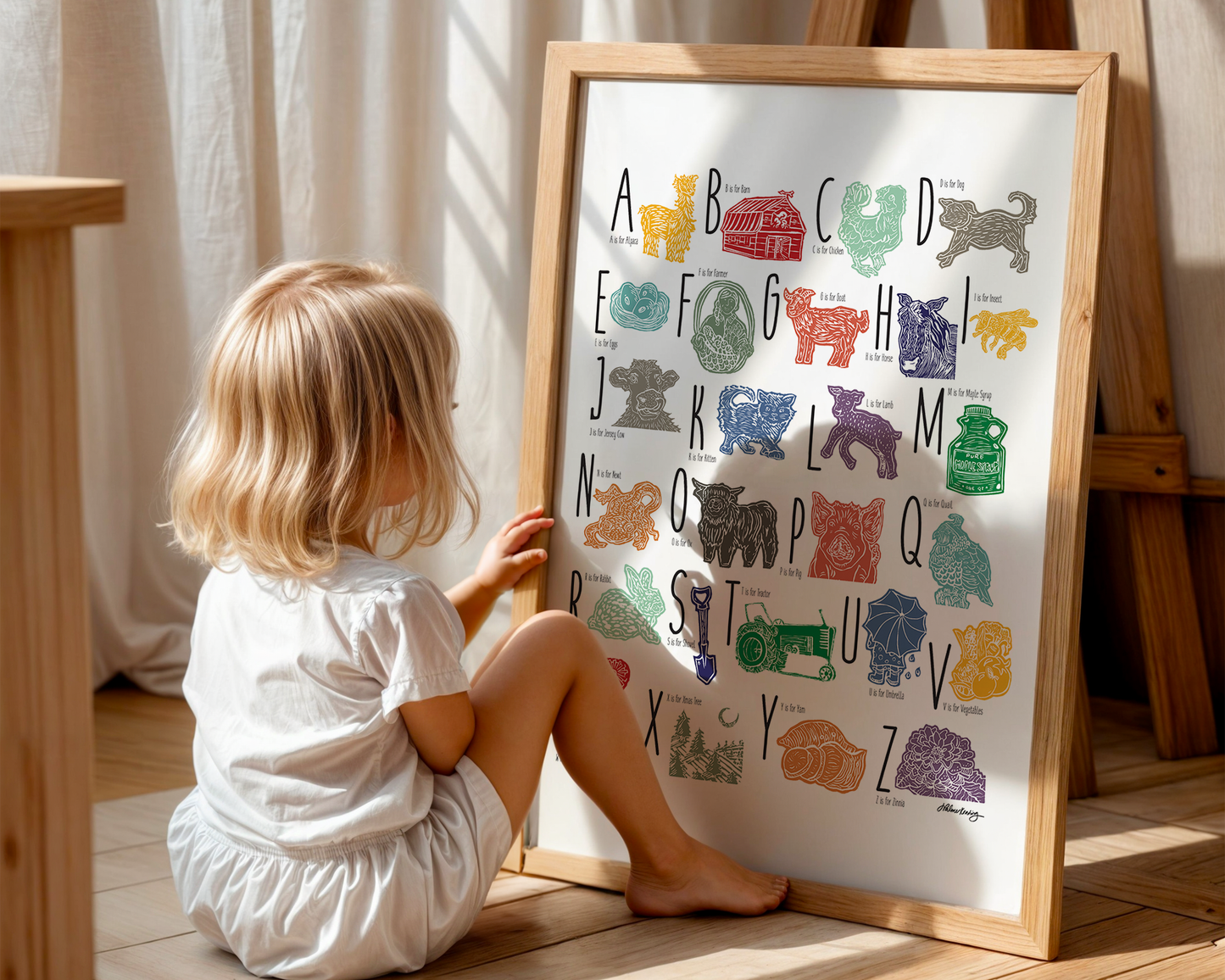 A colorful woodblock print alphabet poster featuring illustrations of farm animals, displayed with a child looking at it.
