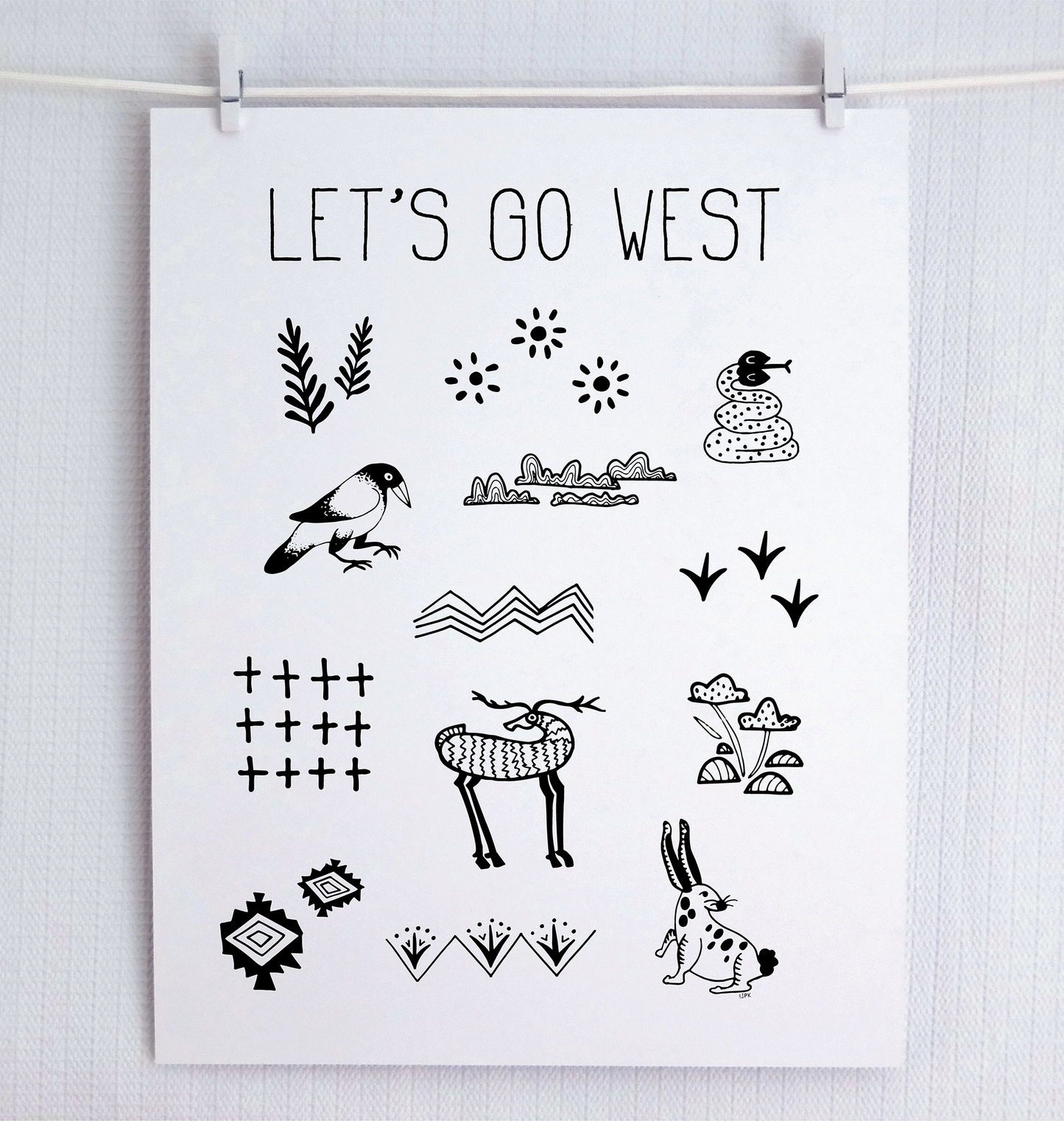 Handwritten thin letters spelling out “Let’s Go West.” Illustrated characters in black on a. white background with clean lines, include snake, crow, deer and rabbit with flora and fauna. Inspired by the southwest and western United States.