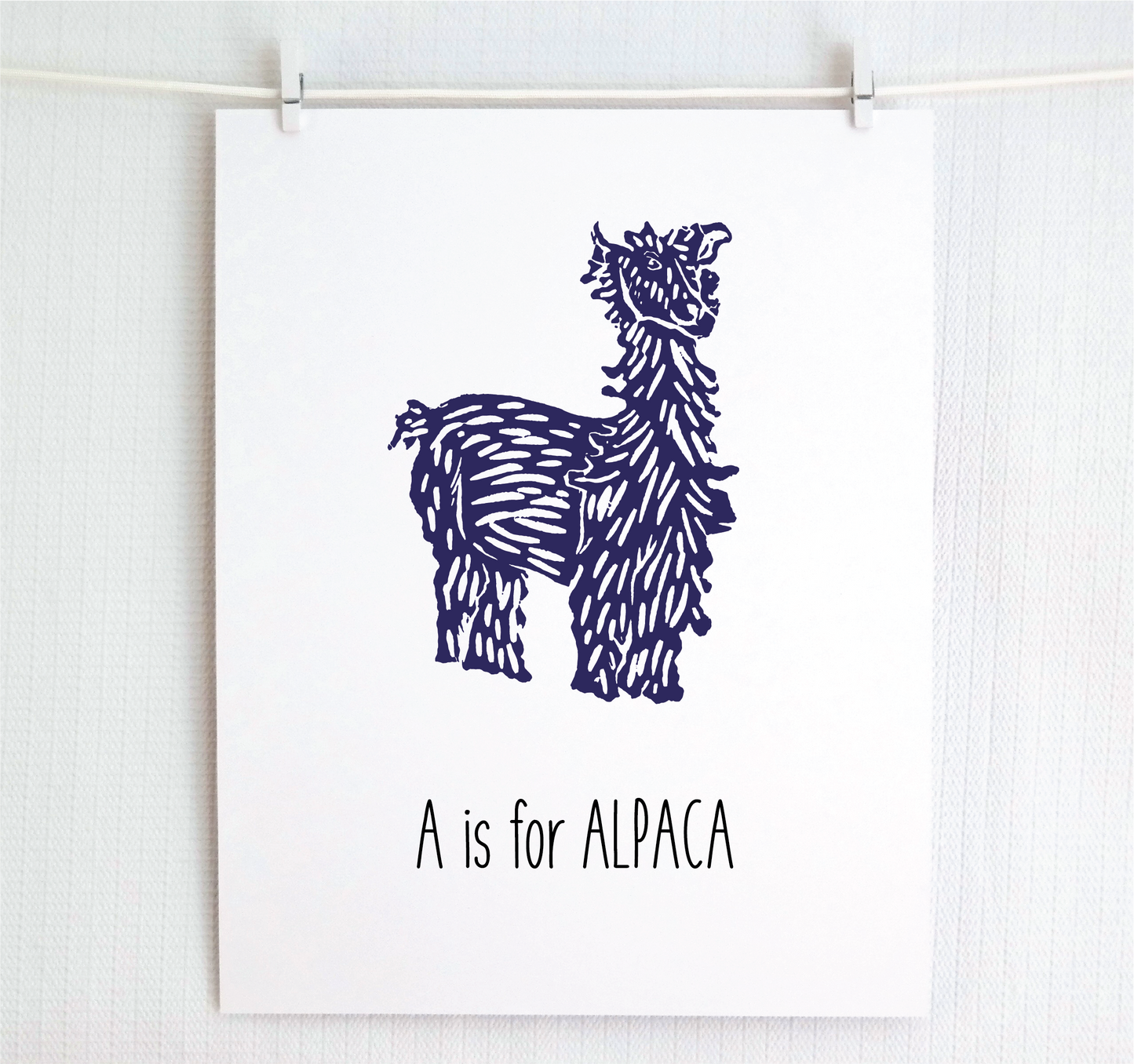 An illustrated alpaca with textured fur stands over hand written style block lettering text that says “A for Alpaca.”