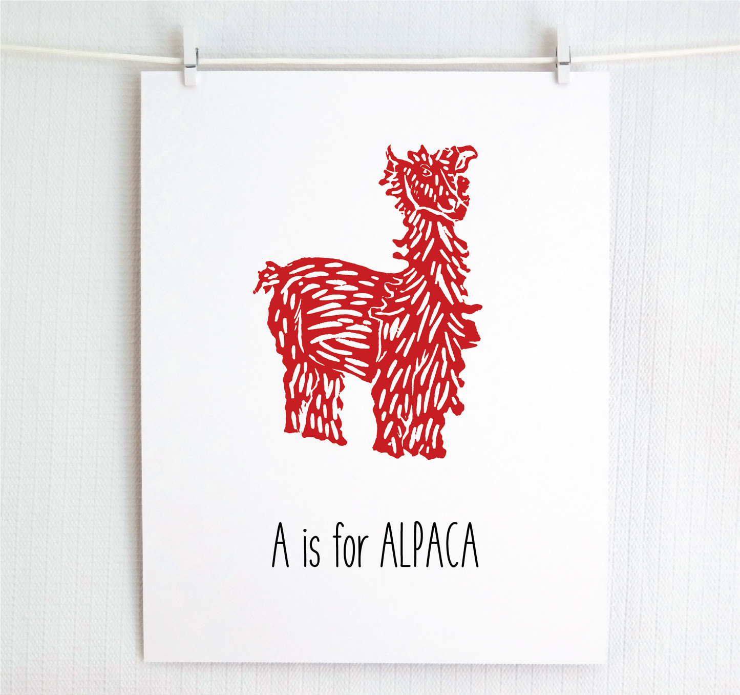 An illustrated alpaca with textured fur stands over hand written style block lettering text that says “A for Alpaca.”