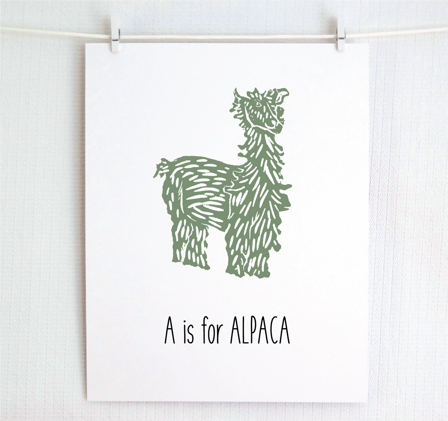 An illustrated alpaca with textured fur stands over hand written style block lettering text that says “A for Alpaca.”