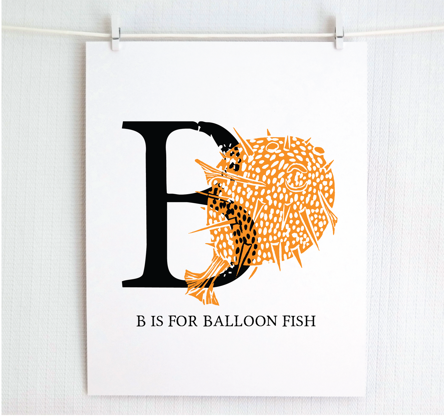An illustrated balloon fish with done in printmaking style over decorative style block lettering text “B” with “B is for Balloon Fish” text printed below.
