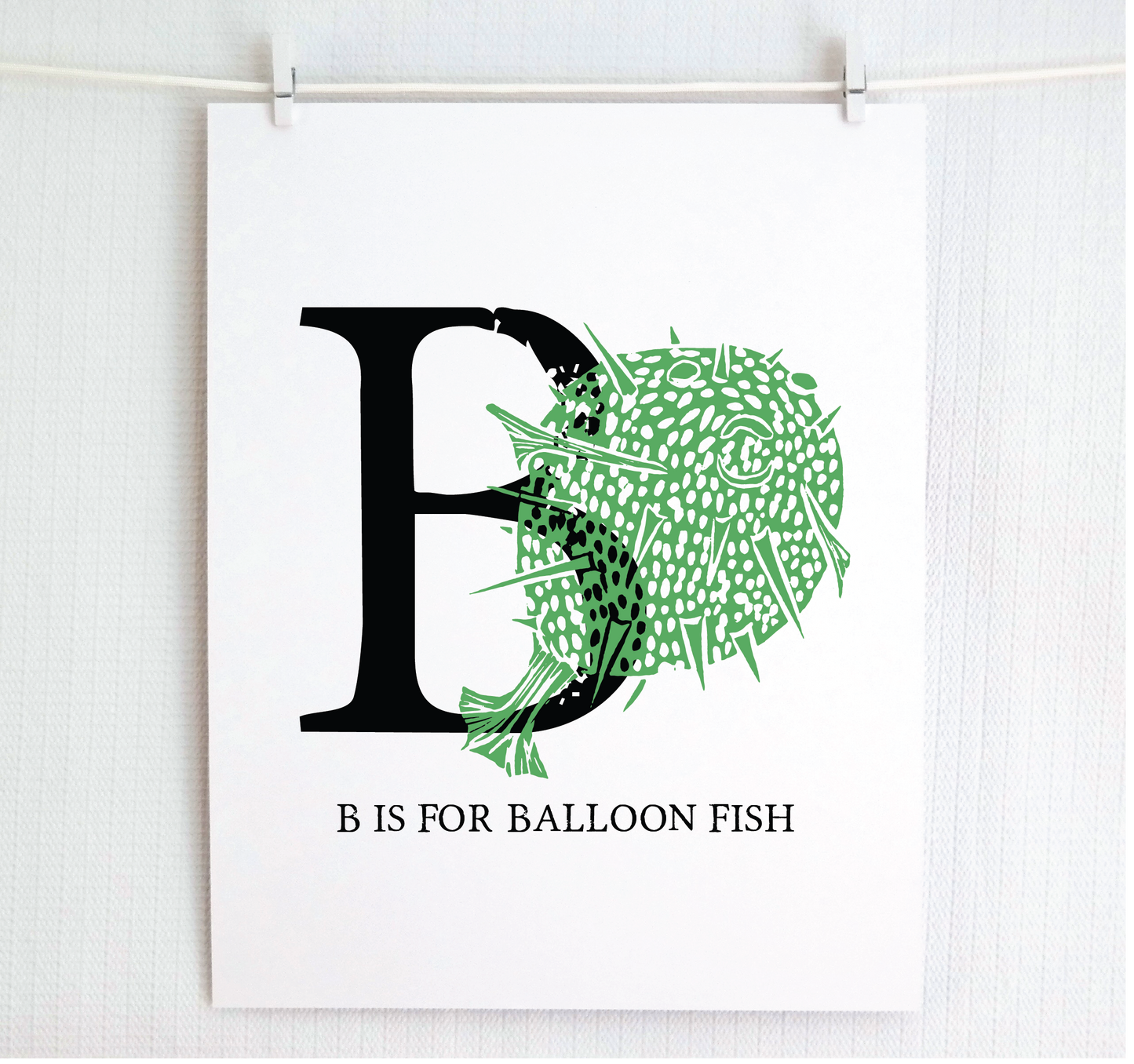 An illustrated balloon fish with done in printmaking style over decorative style block lettering text “B” with “B is for Balloon Fish” text printed below.