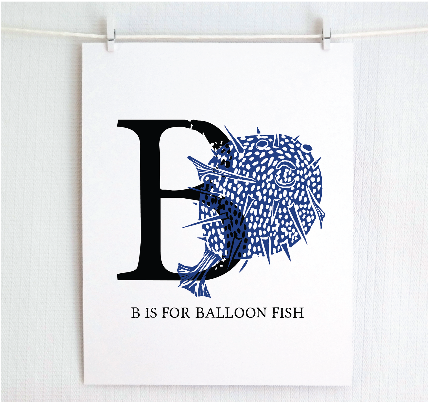 An illustrated balloon fish with done in printmaking style over decorative style block lettering text “B” with “B is for Balloon Fish” text printed below.