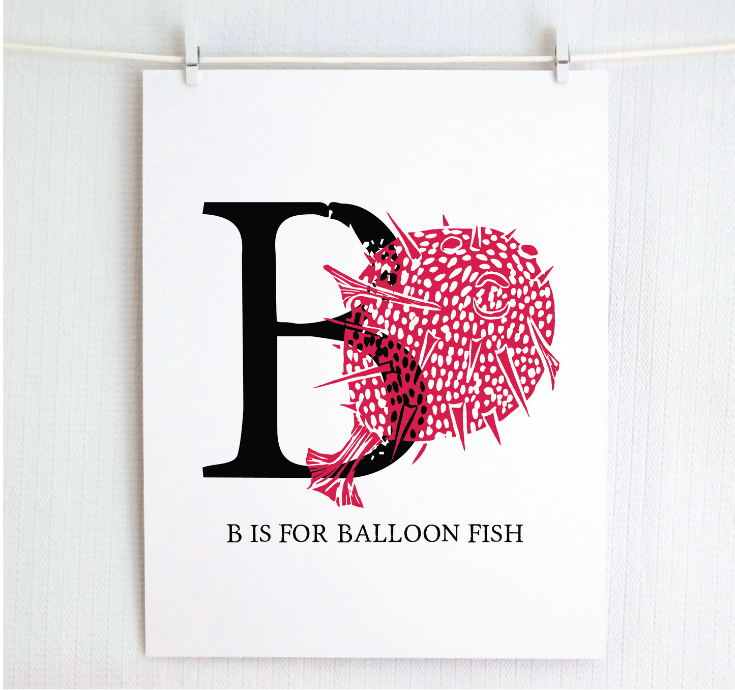 An illustrated balloon fish with done in printmaking style over decorative style block lettering text “B” with “B is for Balloon Fish” text printed below.