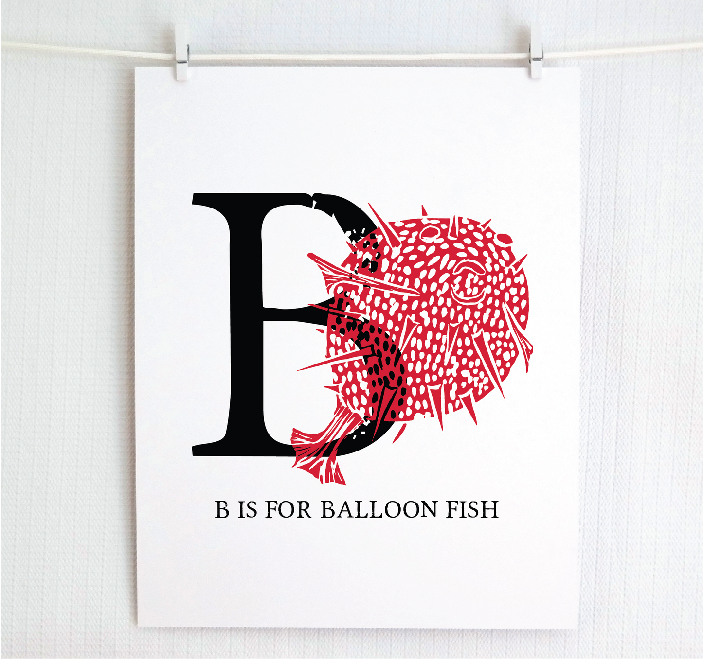 An illustrated balloon fish with done in printmaking style over decorative style block lettering text “B” with “B is for Balloon Fish” text printed below.