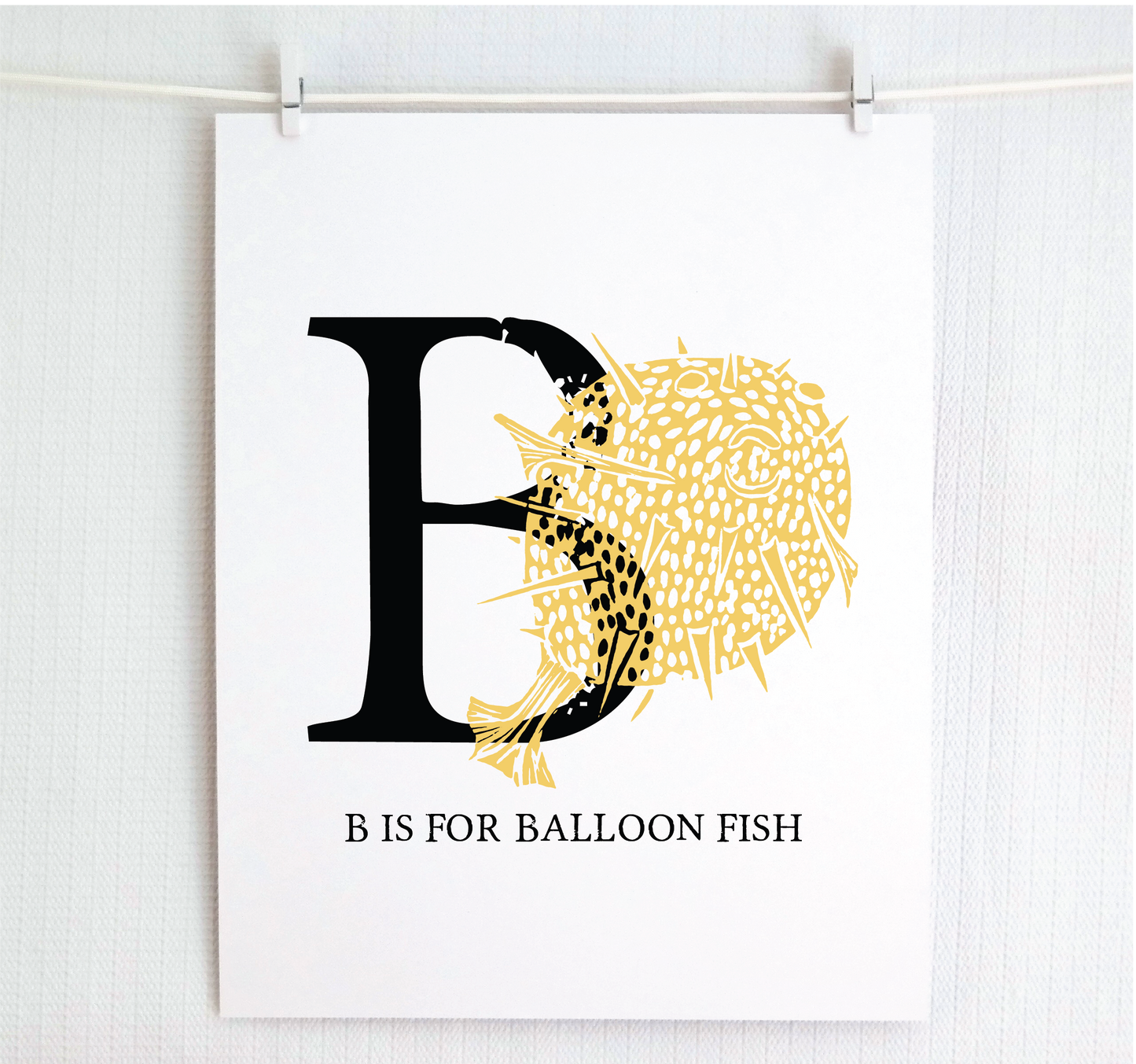An illustrated balloon fish with done in printmaking style over decorative style block lettering text “B” with “B is for Balloon Fish” text printed below.