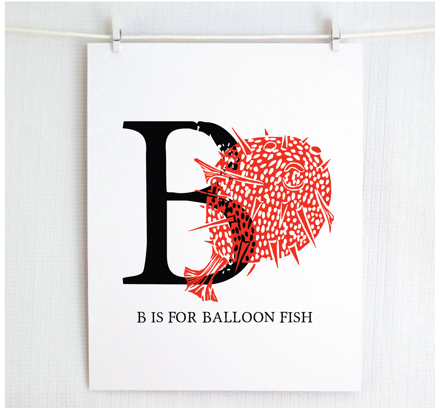 An illustrated balloon fish with done in printmaking style over decorative style block lettering text “B” with “B is for Balloon Fish” text printed below.