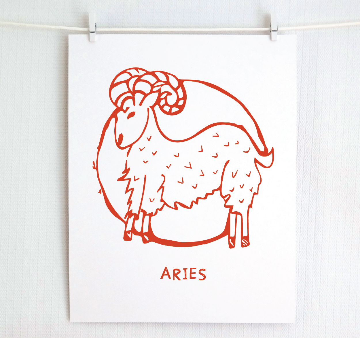 An illustration of the ARIES Zodiac sign as a ram, printed on paper with the word ‘ARIES’ at the bottom in red.