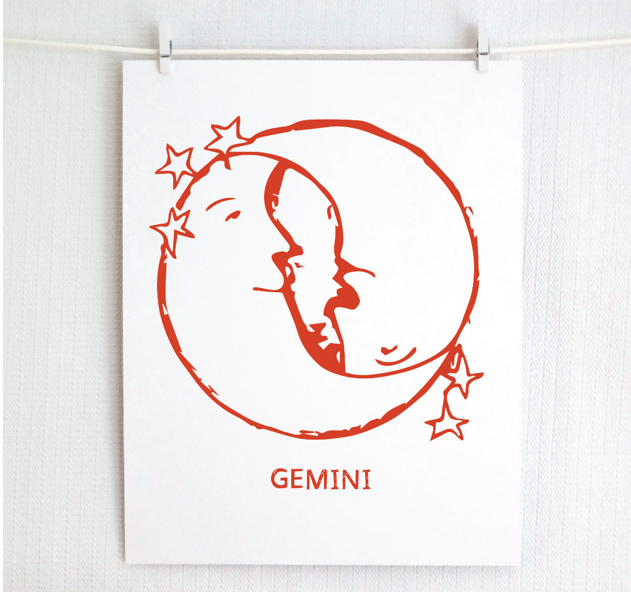 An illustration of the GEMINI Zodiac sign as crescent moons, printed on paper with the word 'GEMINI’ at the bottom in red.