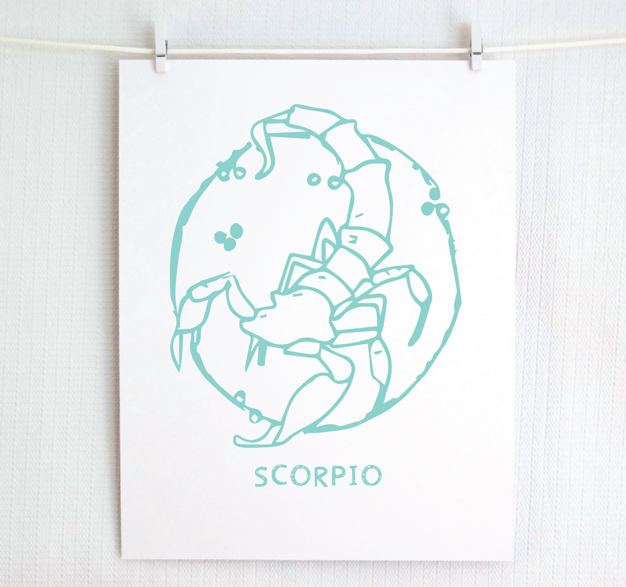 An illustration of the SCORPIO Zodiac sign as a scorpion, printed on paper with the word ‘SCORPIO’ at the bottom in teal.