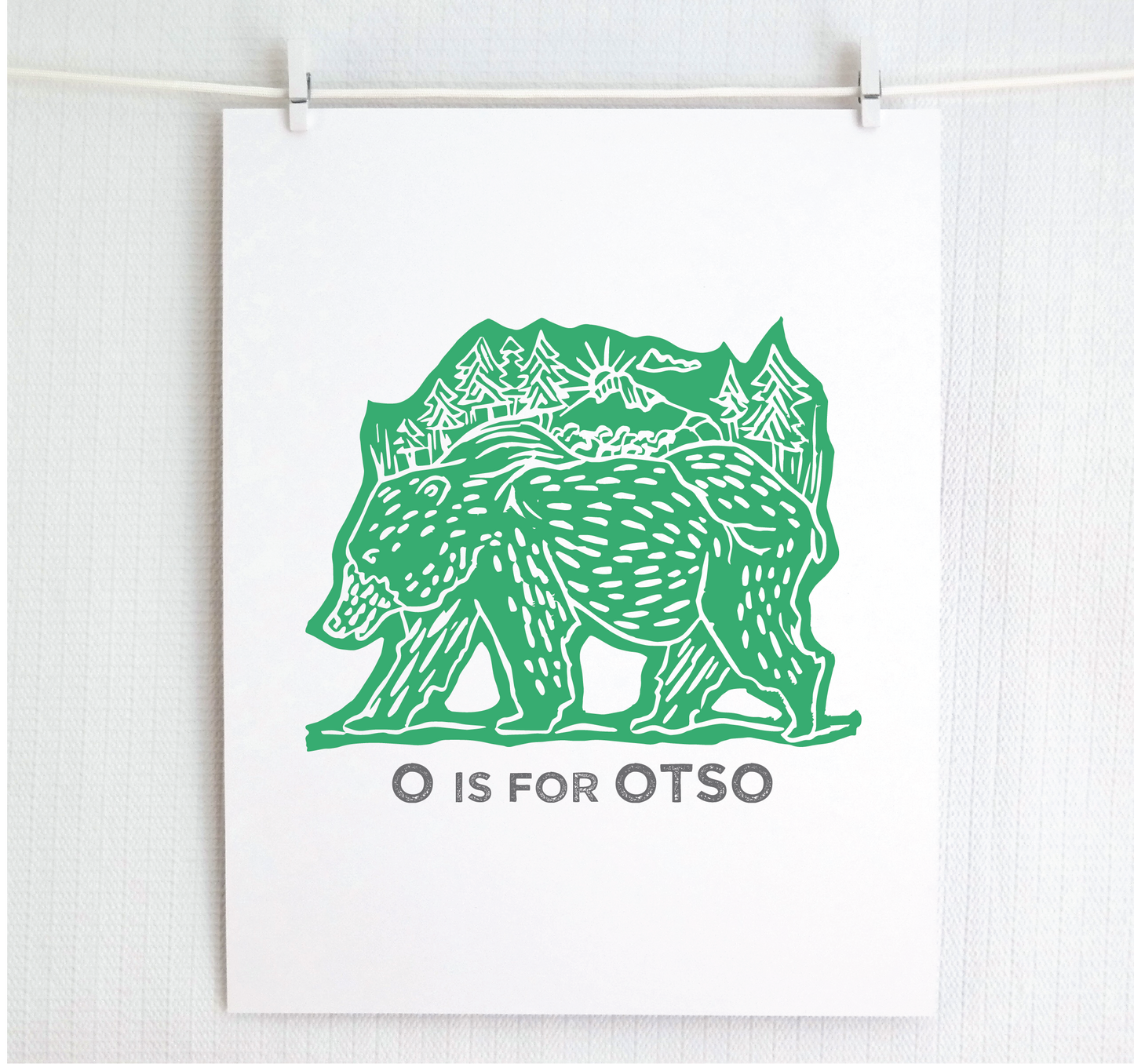 Friendly illustrated bear walking with the forest growing on his back. “O is for Otso” text in a gray block font below.