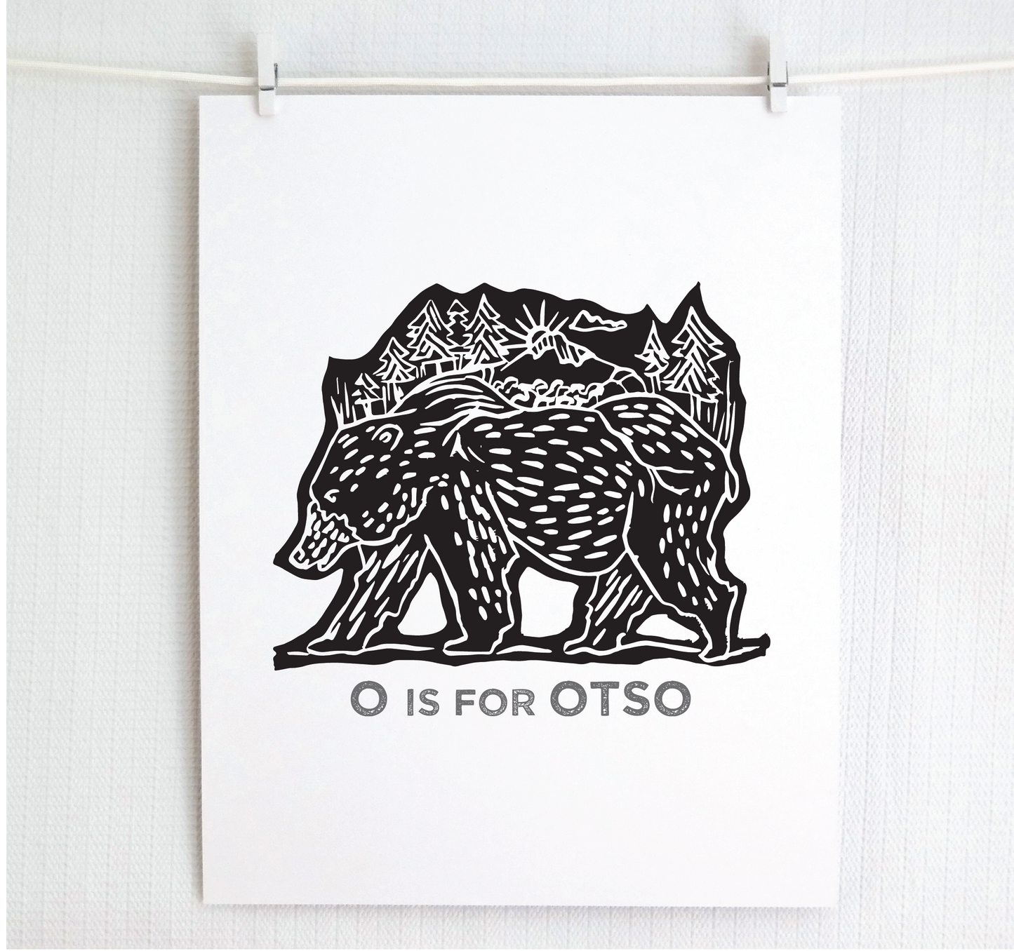 Friendly illustrated bear walking with the forest growing on his back. “O is for Otso” text in a gray block font below.