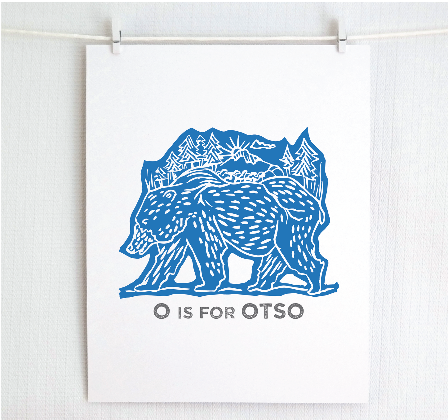 Friendly illustrated bear walking with the forest growing on his back. “O is for Otso” text in a gray block font below.