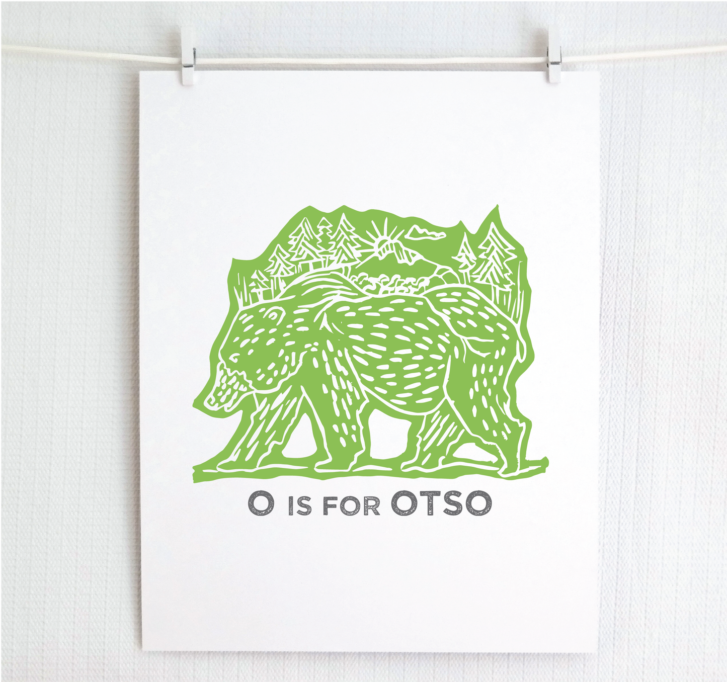 Friendly illustrated bear walking with the forest growing on his back. “O is for Otso” text in a gray block font below.