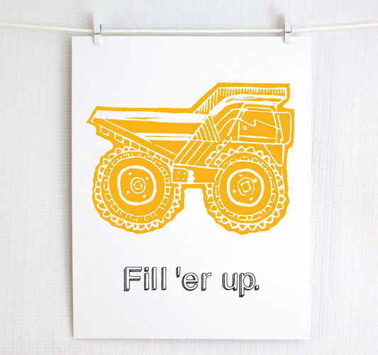 A white art print clipped to a white wall, featuring a yellow block-print style illustration of a dump truck with the text 'Fill 'er up.' underneath.