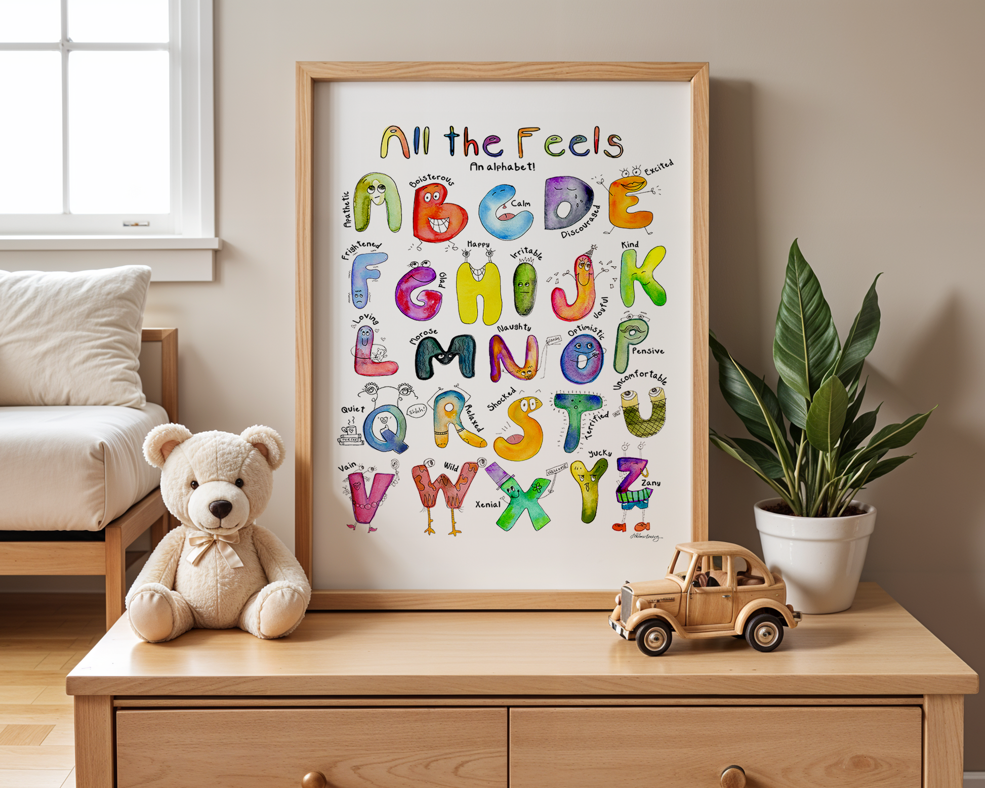 Framed alphabet poster with colorful letters on a wooden dresser with toys and a plant.