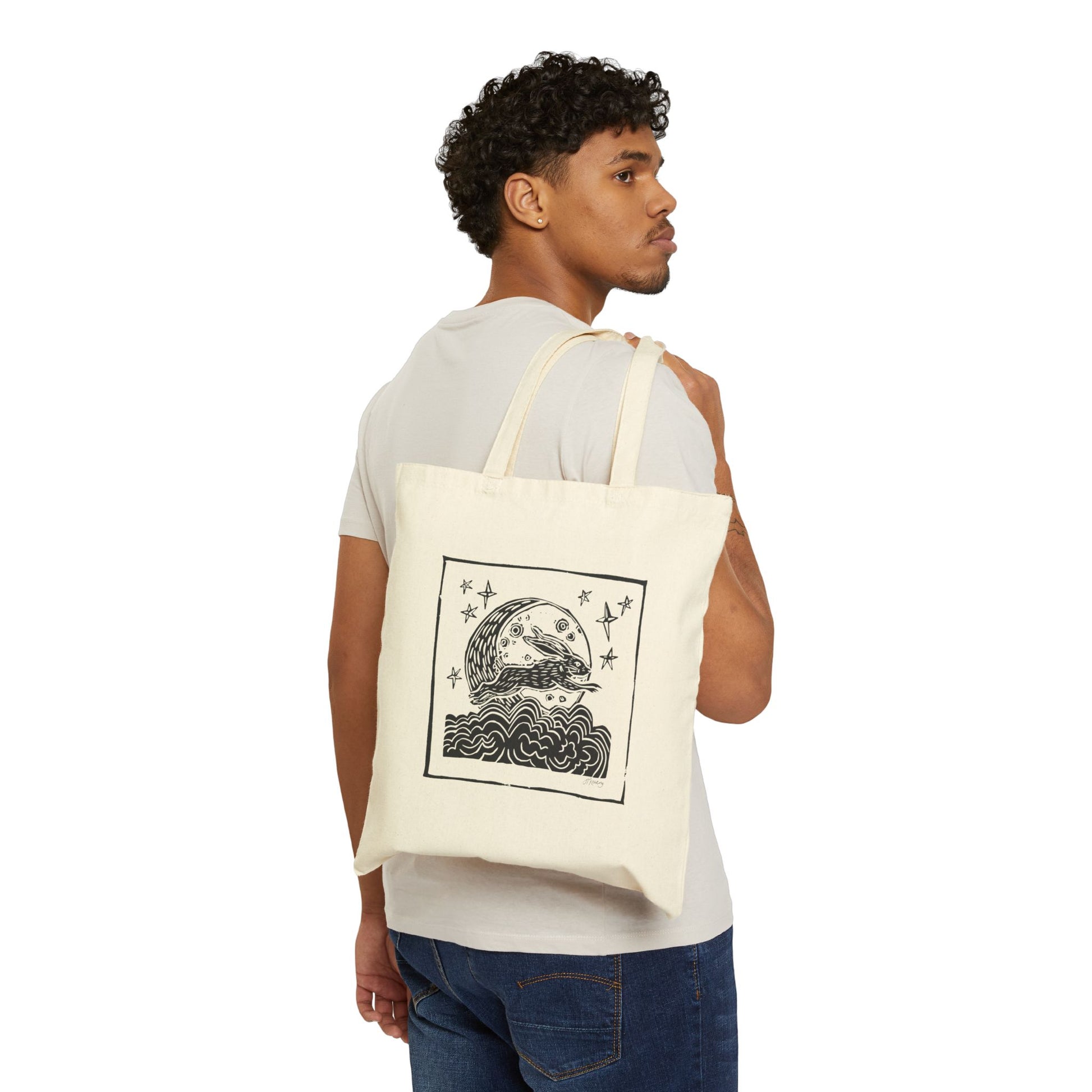 Man carrying a tote bag with a bunny moon graphic design on a white background