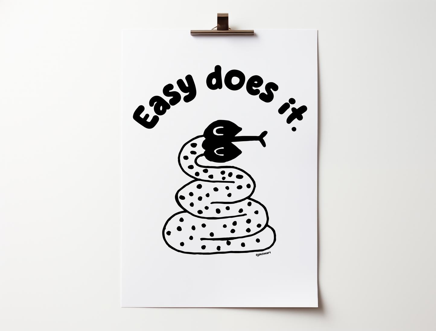 Handwritten thin letters spelling out “Easy Does It.” Illustrated snake character in black on a white background with clean lines. Inspired by the southwest and western United States.
