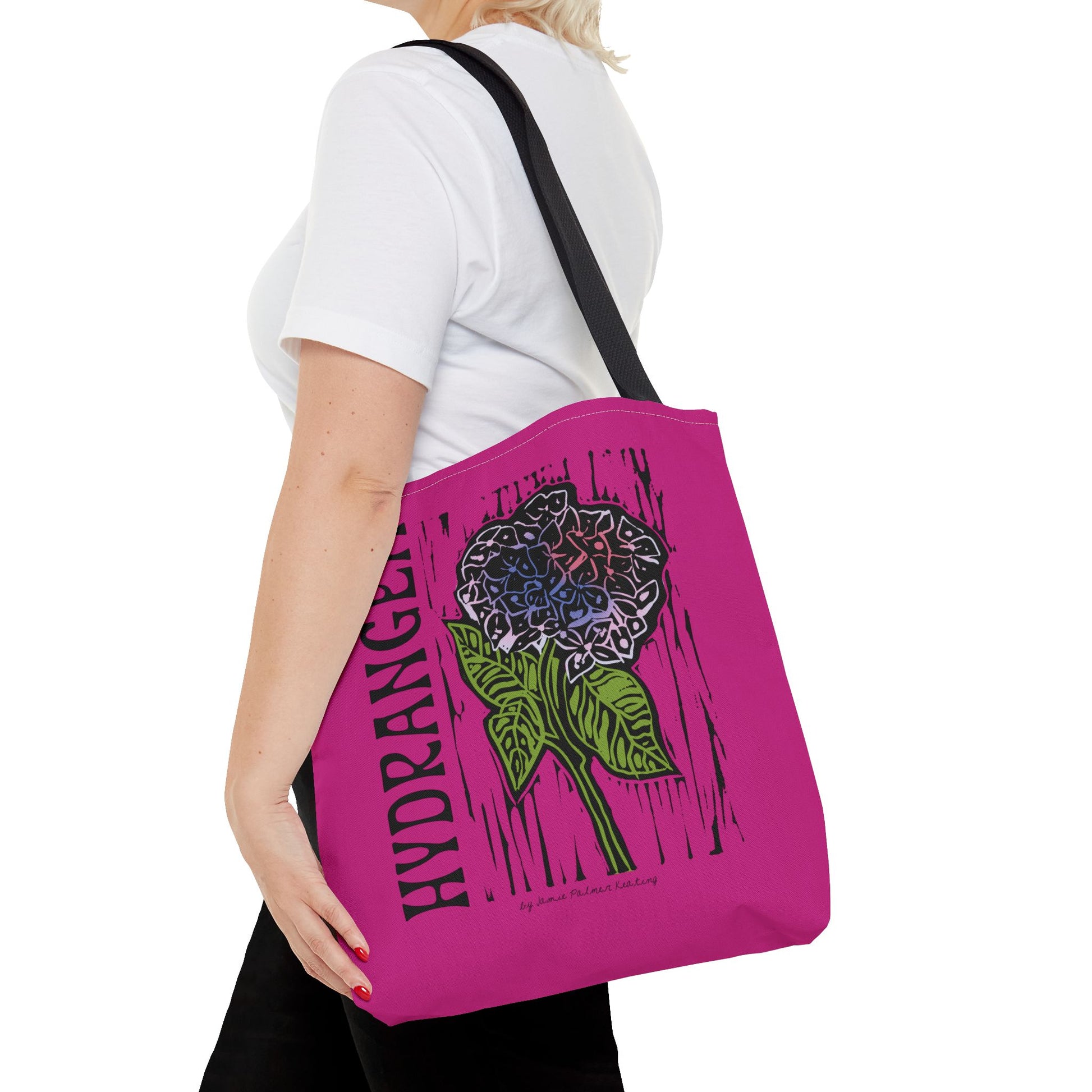Person holding a pink tote bag with a floral design and text.