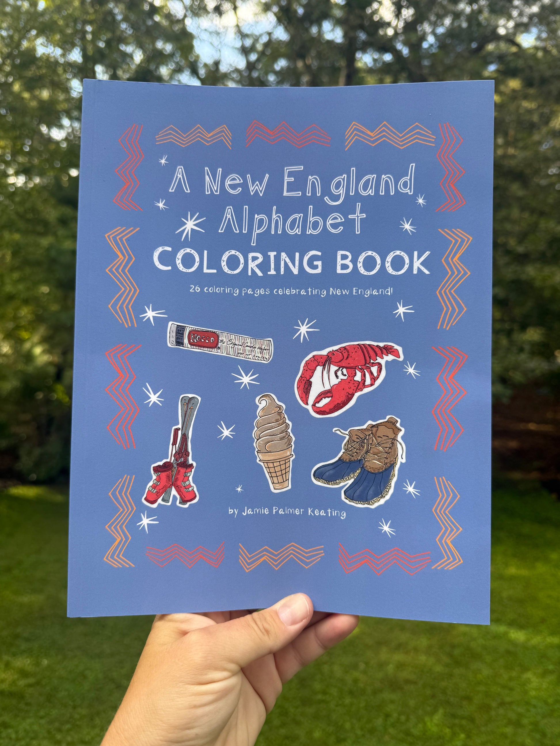 Coloring book titled 'A New England Alphabet Coloring Book' held against a natural background