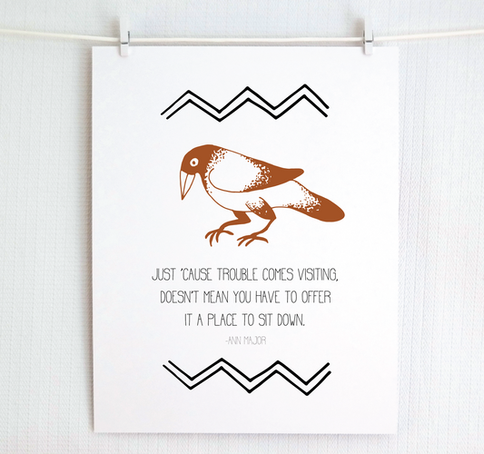 An illustrated print featuring a crow with the phrase 'Just 'cause trouble comes visiting, doesn't mean you have to offer it a place to sit down.'.