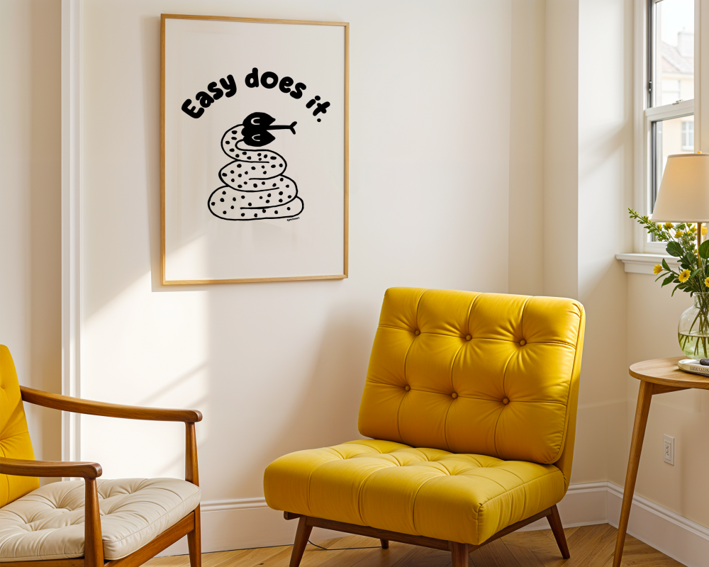 Room with a yellow chair and a framed print on the wall with handwritten thin letters spelling out “Easy Does It.” Illustrated snake character in black on a white background with clean lines. Inspired by the swestern United States.

