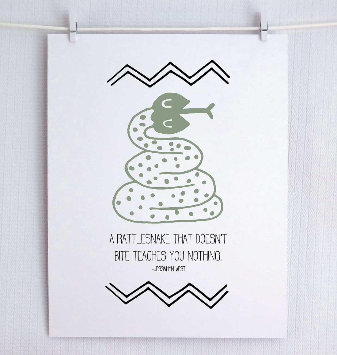 An illustrated print featuring a green snake with text 'A RATTLESNAKE THAT DOESN'T BITE TEACHES YOU NOTHING' on a white background with black decorative patterns.