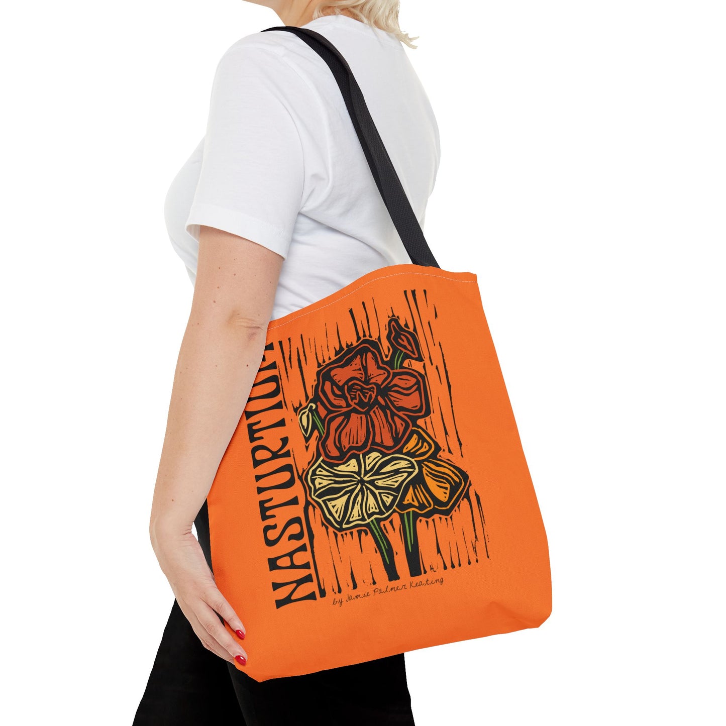 Person holding an orange tote bag with floral design and text.
