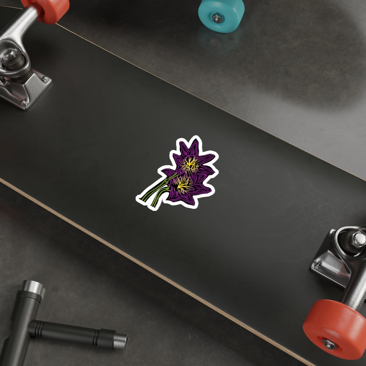 Skateboard with a purple flower sticker on a black deck