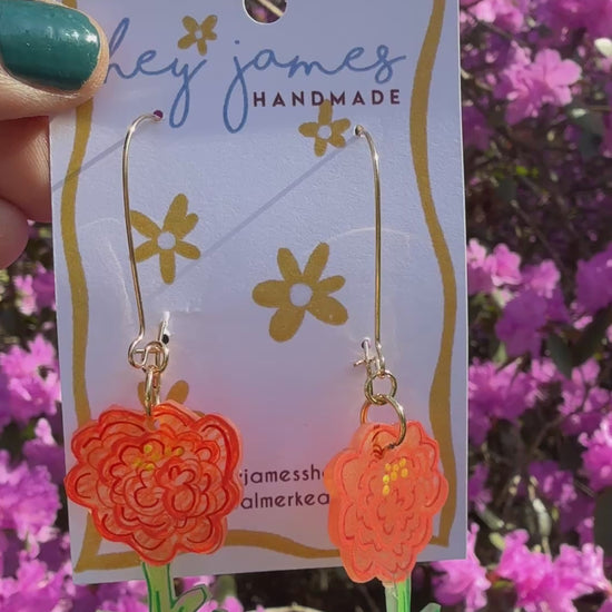 Hand holding a card with floral earrings against a background of pink flowers video