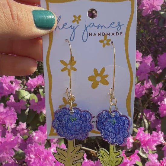 Hand holding a card with floral earrings against a background of pink flowers video