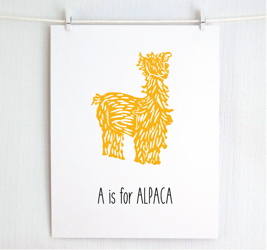 An illustrated alpaca with textured fur stands over hand written style block lettering text that says “A for Alpaca.”
