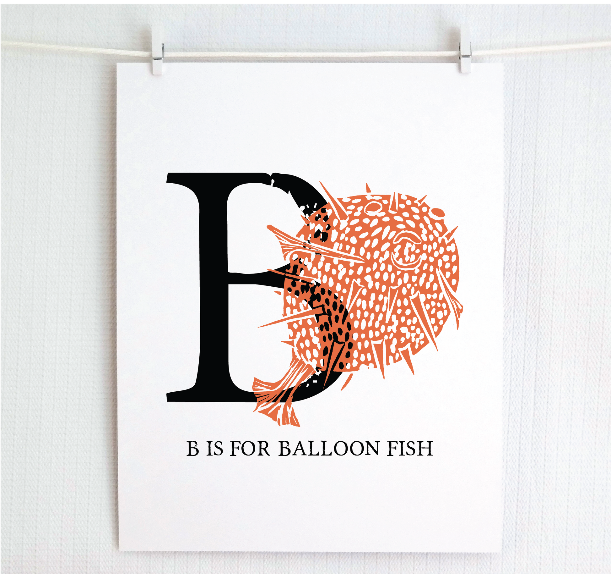 An illustrated balloon fish with done in printmaking style over decorative style block lettering text “B” with “B is for Balloon Fish” text printed below.
