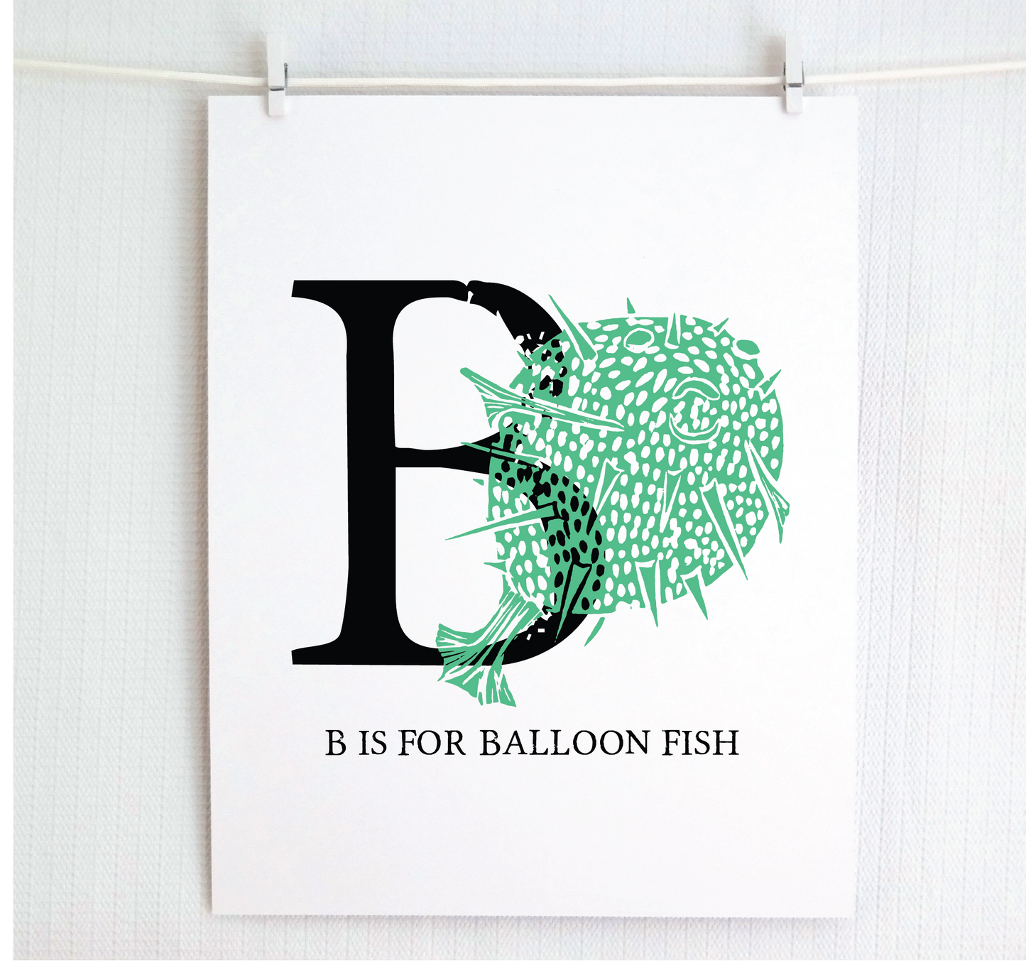 An illustrated balloon fish with done in printmaking style over decorative style block lettering text “B” with “B is for Balloon Fish” text printed below.
