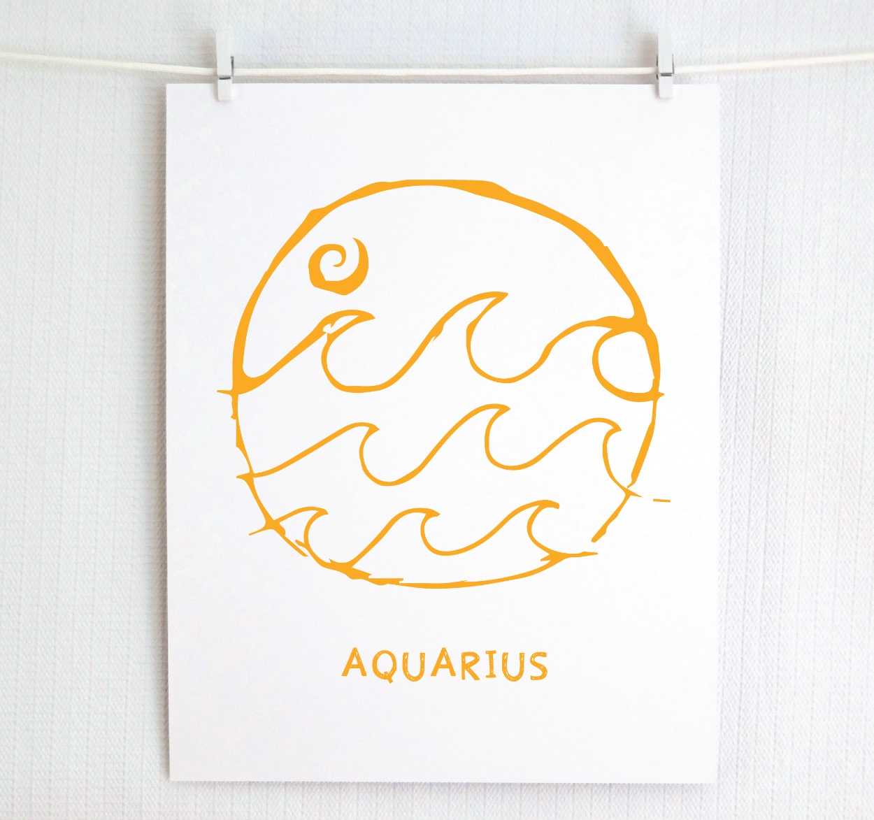 An illustration of the Aquarius Zodiac sign, printed on paper with the word 'AQUARIUS' at the bottom in gold