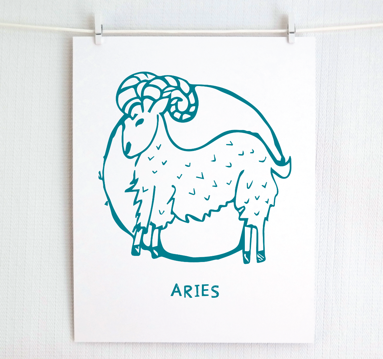 An illustration of the ARIES Zodiac sign as a ram, printed on paper with the word ‘ARIES’ at the bottom in dark teal.