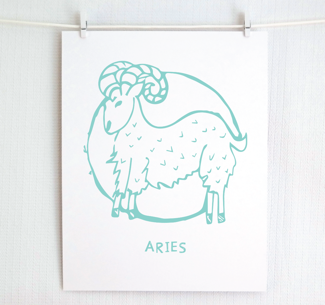An illustration of the ARIES Zodiac sign as a ram, printed on paper with the word ‘ARIES’ at the bottom in teal.