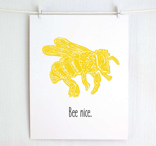 An illustrated bee with textured wings and body hovers over hand written style block lettering text that says “Bee nice.”
