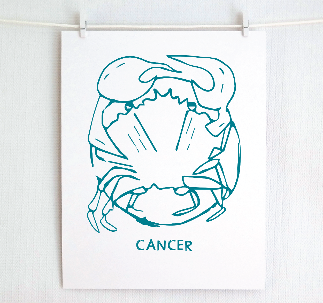 An illustration of the CANCER Zodiac sign as a crab, printed on paper with the word ‘CANCER’ at the bottom in dark teal.