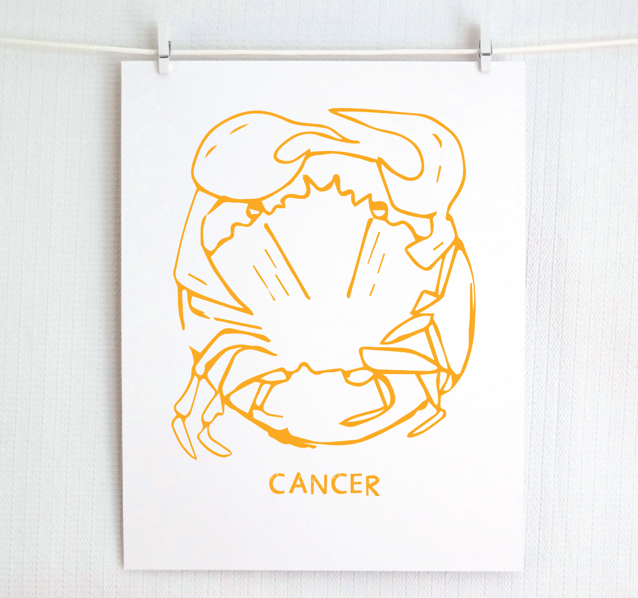 An illustration of the CANCER Zodiac sign as a crab, printed on paper with the word ‘CANCER’ at the bottom in gold.