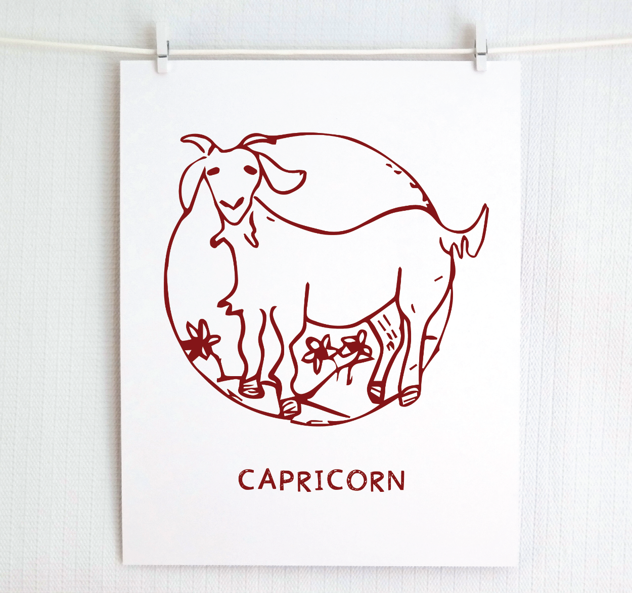 An illustration of the CAPRICORN Zodiac sign as a goat, printed on paper with the word ‘CAPRICORN’ at the bottom in cranberry.