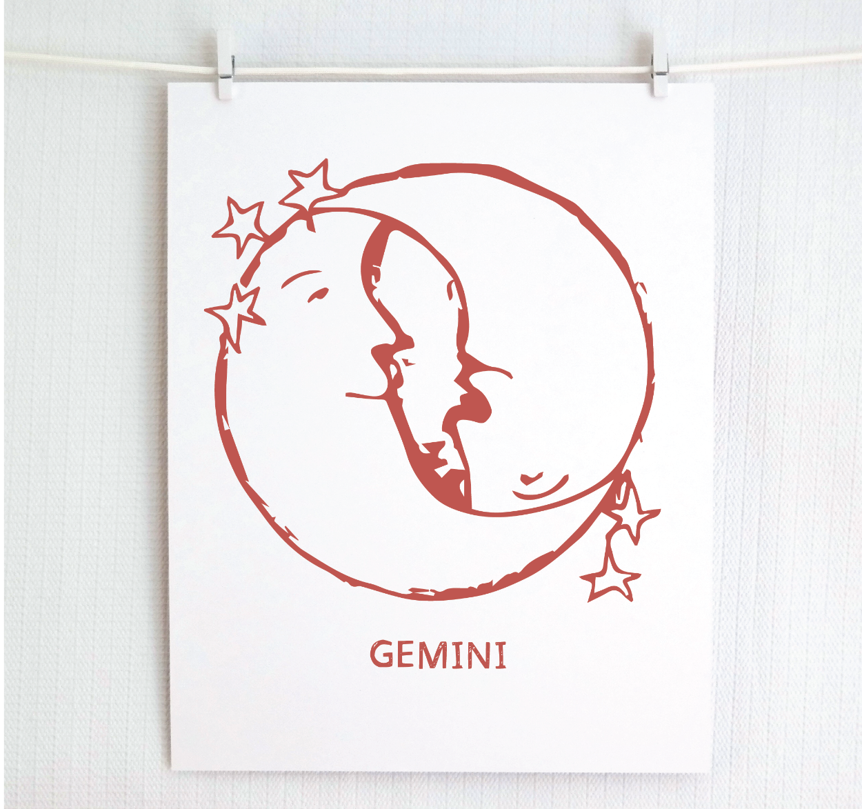 An illustration of the GEMINI Zodiac sign as crescent moons, printed on paper with the word 'GEMINI’ at the bottom in blush.