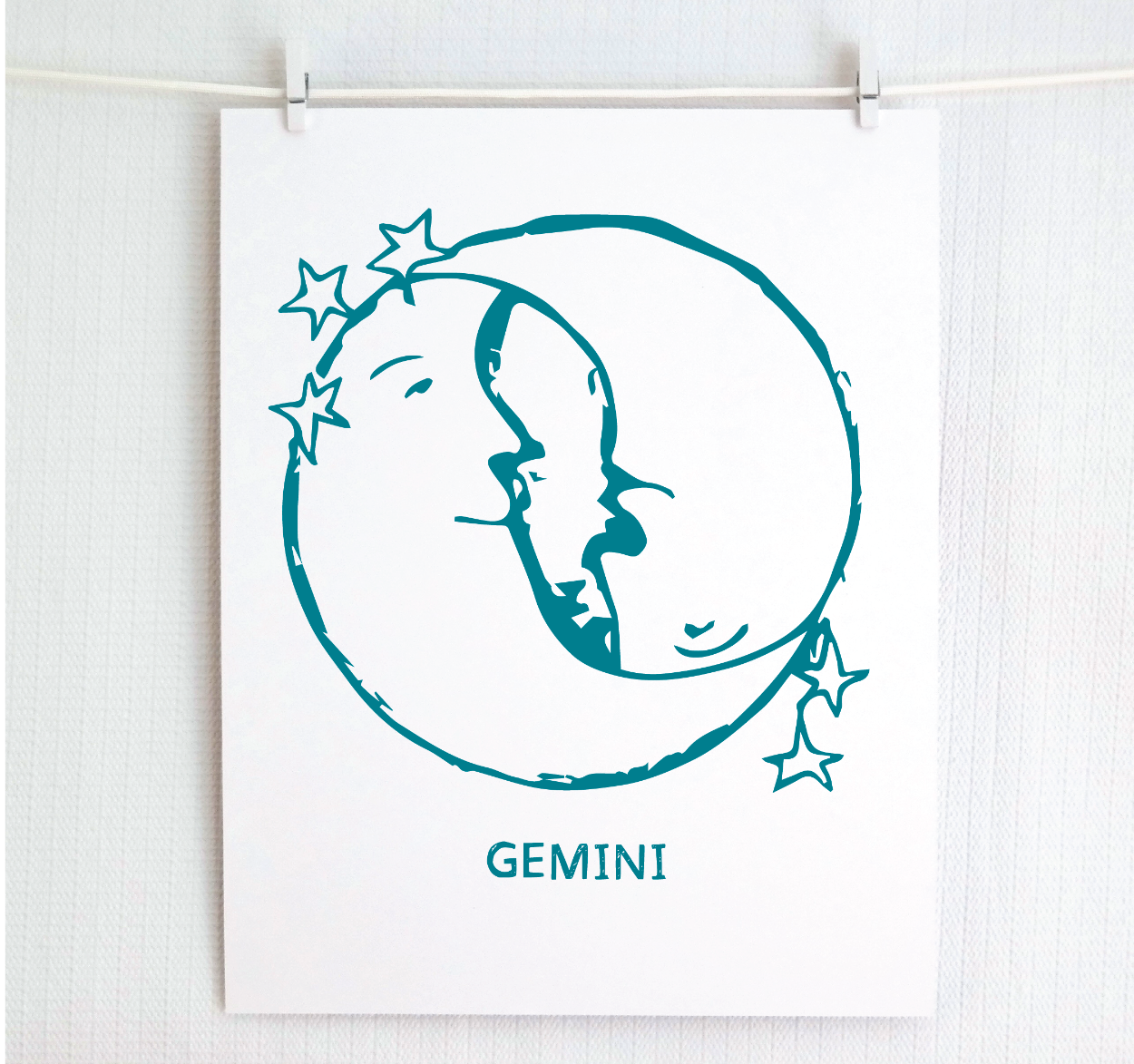 An illustration of the GEMINI Zodiac sign as crescent moons, printed on paper with the word 'GEMINI’ at the bottom in dark teal.