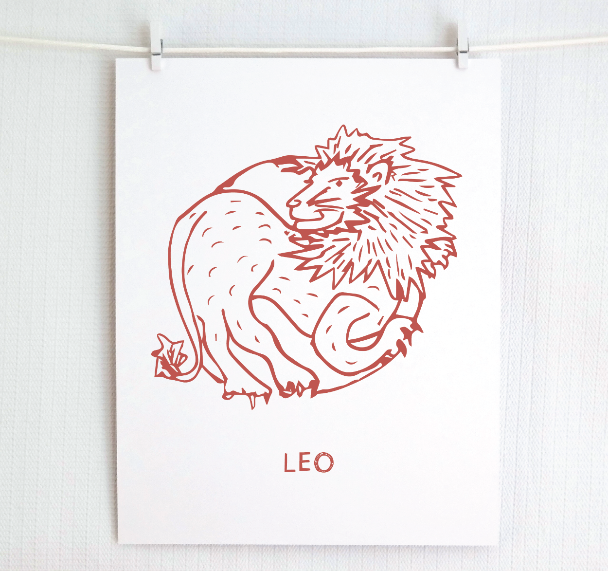 An illustration of the LEO Zodiac sign as a lion, printed on paper with the word ‘LEO’ at the bottom in blush.
