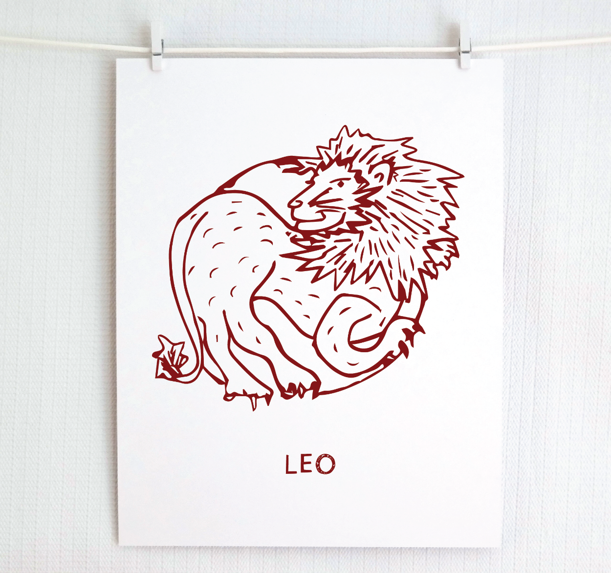 An illustration of the LEO Zodiac sign as a lion, printed on paper with the word ‘LEO’ at the bottom in cranberry.