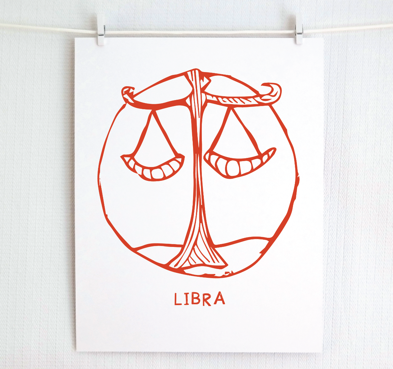 An illustration of the LIBRA Zodiac sign, printed on paper with the word 'LIBRA’ at the bottom in red.