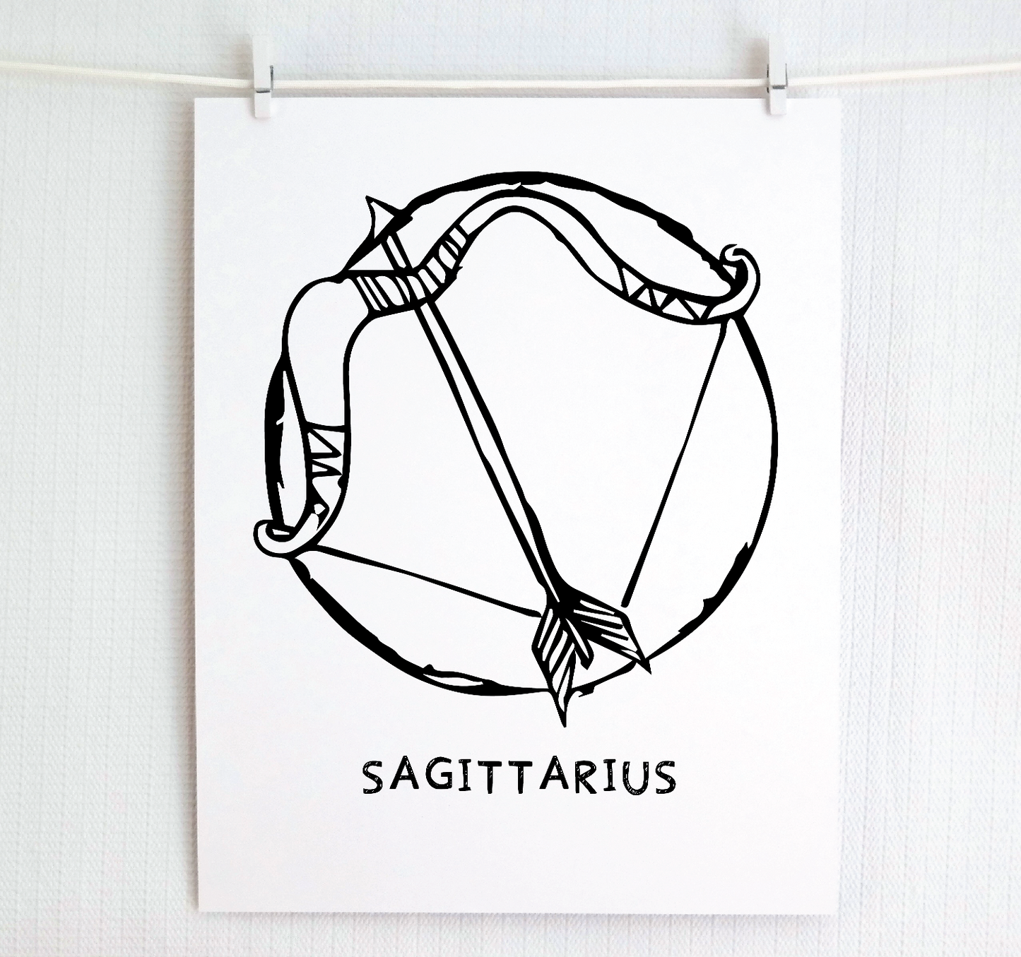 An illustration of the SAGITTARIUS Zodiac sign as a bow and arrow, printed on paper with the word ‘SAGITTARIUS’ at the bottom.